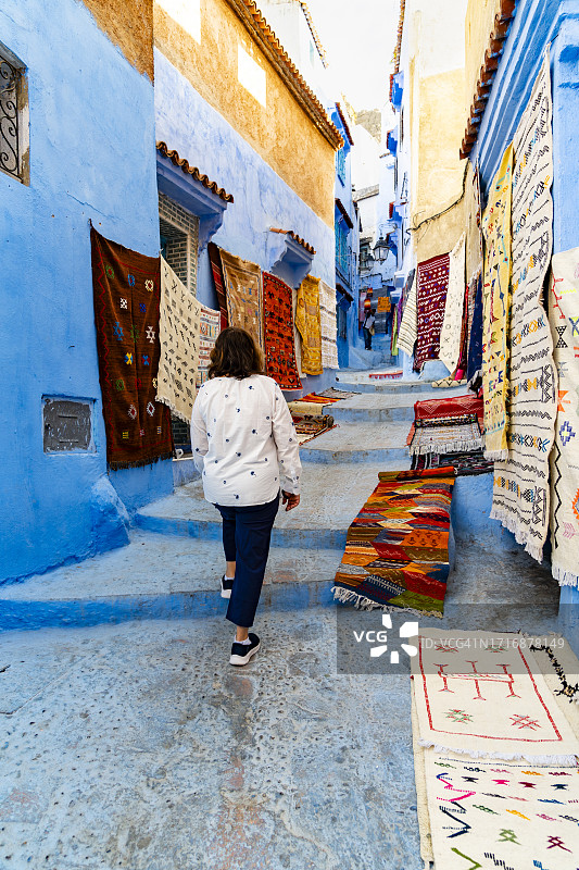 女子走在摩洛哥舍夫沙万的巷子里图片素材