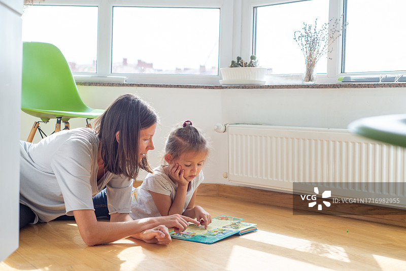 年轻女子在房子地板上和孩子一起玩拼图玩具图片素材