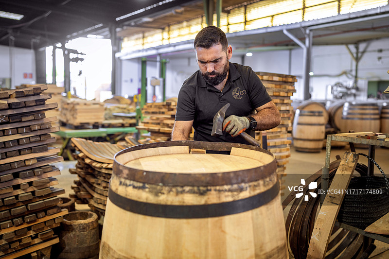 在赫雷斯的桶匠作坊里，工人师傅正在制作白兰地木桶，用铁环压缩橡木板图片素材