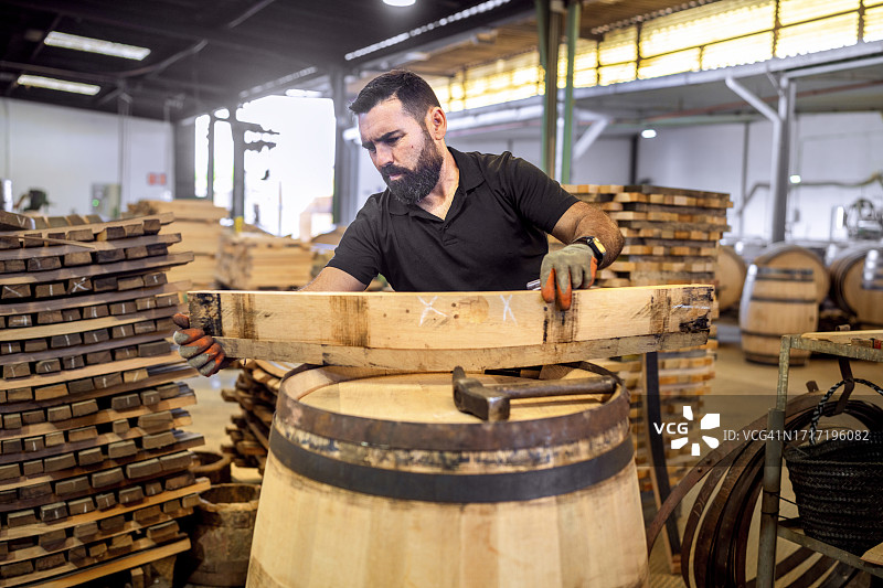 在赫雷斯（雪利酒产地）的桶匠作坊里，工人用铁环压缩橡木板，制作白兰地木桶图片素材