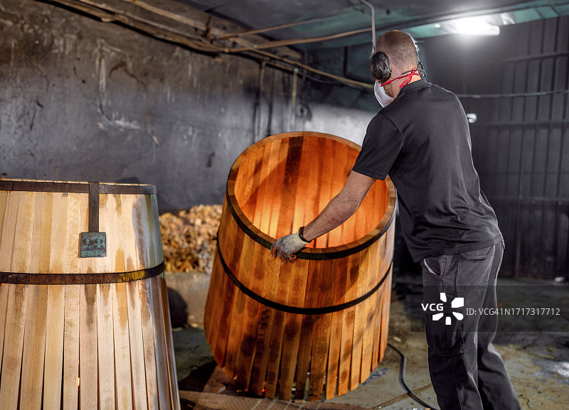 赫雷斯（雪利酒）的桶匠将一个桶放在烤箱上，使木材和木板适应并塑造桶图片素材