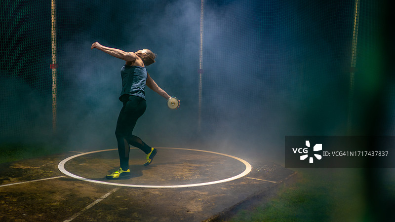 女运动员在户外夜晚投掷铁饼图片素材