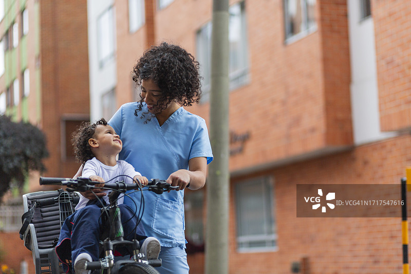 一位穿着医疗制服的非洲裔医生在波哥大的街道上骑着自行车，接她4岁的儿子图片素材