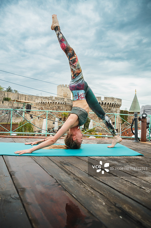 在垫子上做单腿下犬式的女人，户外瑜伽练习图片素材