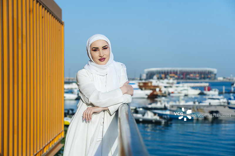 站在河边船只旁的快乐阿拉伯女人图片素材