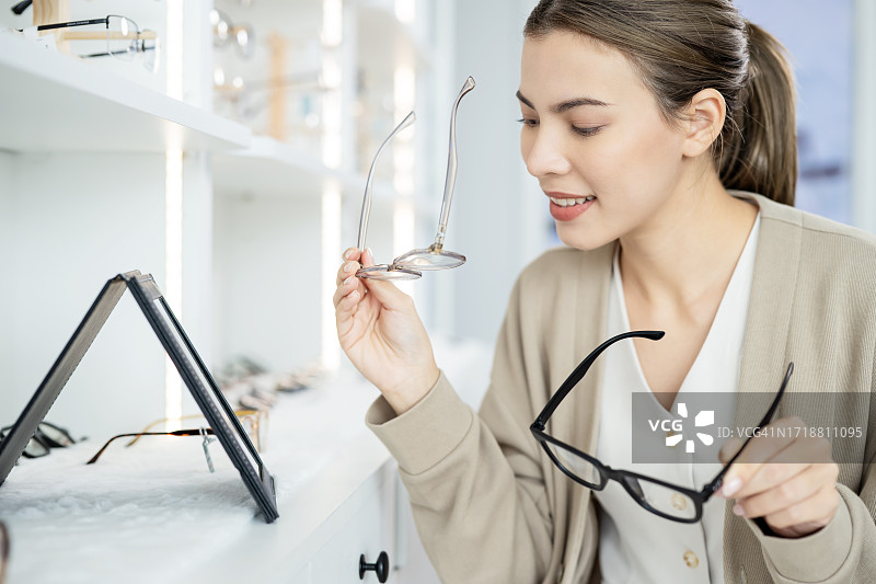 戴眼镜提升自信：女顾客在眼镜店试戴并选择新款眼镜图片素材