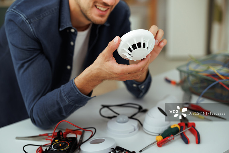 年轻英俊的男子在家修理烟雾传感器图片素材