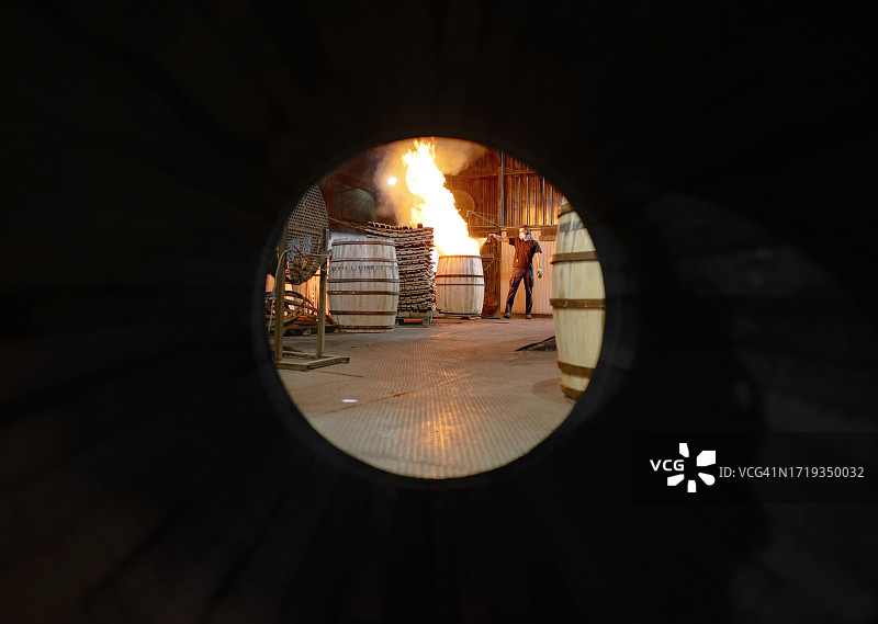 在赫雷斯，一名制桶工人正在用火烘烤桶的内部，并用水进行搅拌图片素材