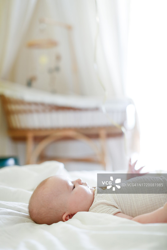 甜蜜的梦：躺在明亮托儿所卧室里的胖乎乎的婴儿，竖版构图和留白图片素材