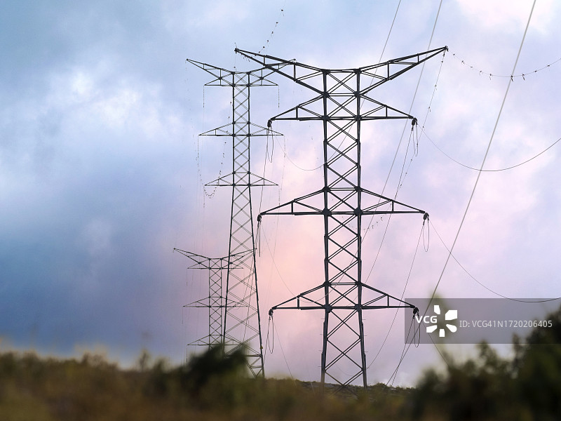 夕阳下，发电站旁的高压电塔图片素材