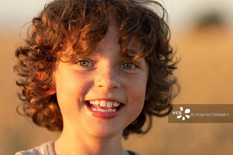在麦田里微笑的8岁卷发男孩图片素材