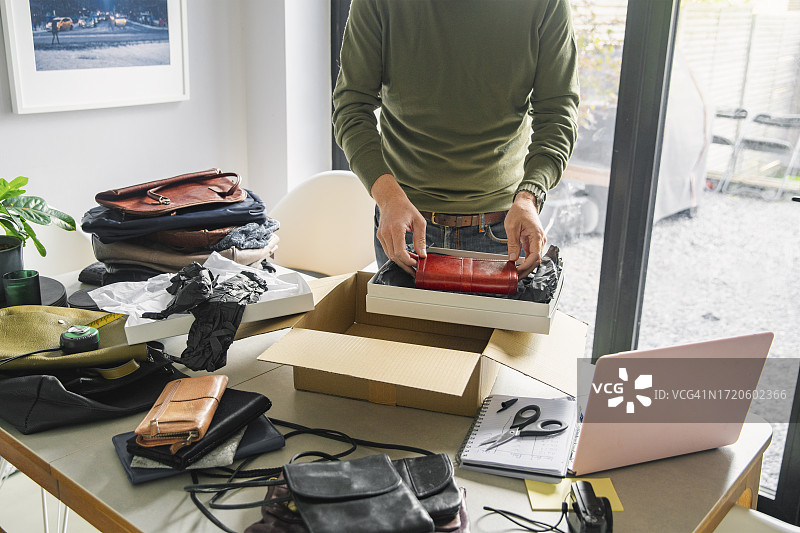 一位身份不明的男人打包刚在网上卖掉的二手钱包图片素材