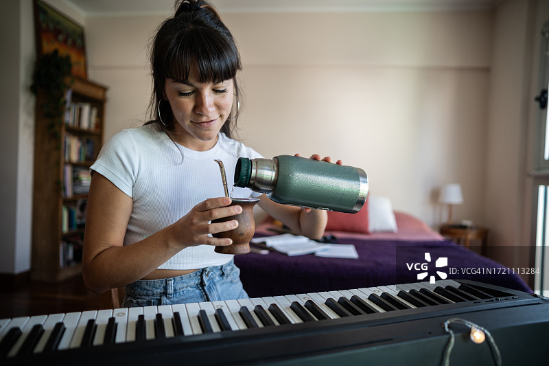 年轻女音乐家在公寓中准备马黛茶图片素材