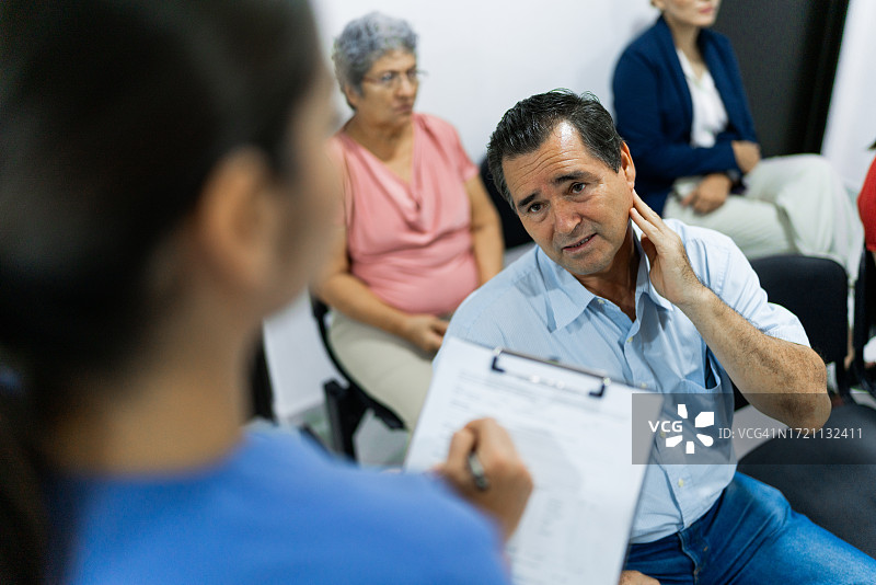 中年男人在医院候诊室与女护士交谈图片素材