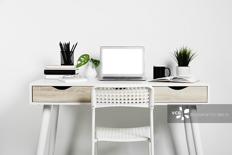 舒适的办公空间：笔记本电脑、植物和文具图片素材