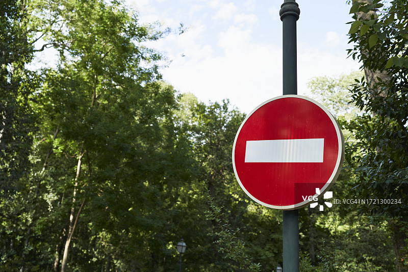 公园里金属柱子上带白线的红色交通标志图片素材