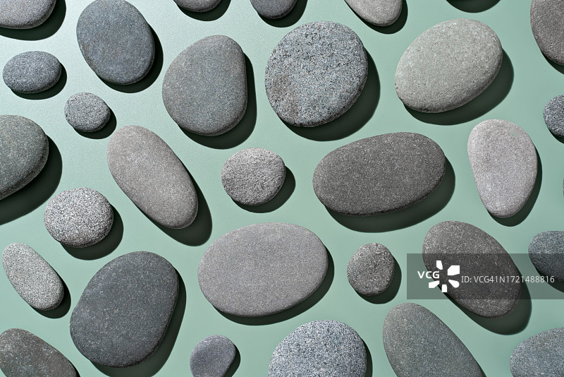 绿色背景上的灰色鹅卵石平铺图片素材