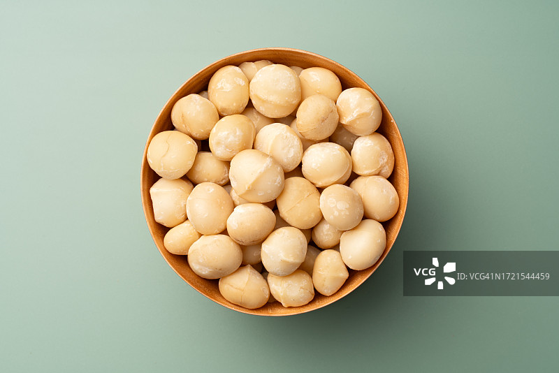 绿色背景木碗中的澳洲坚果图片素材