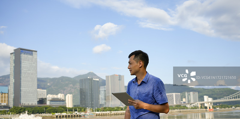 年轻男人在户外使用平板电脑工作图片素材