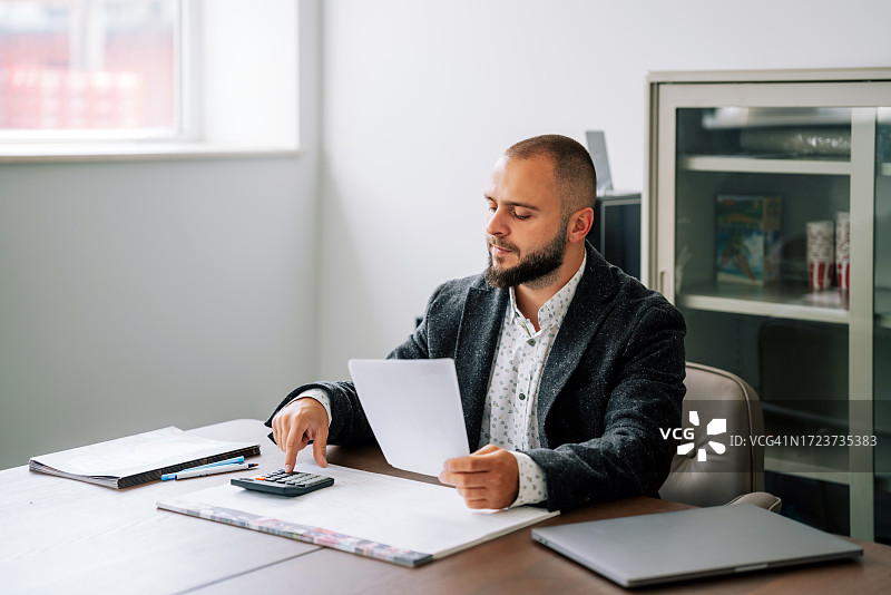 年轻有为的商人在办公室里进行财务计算图片素材