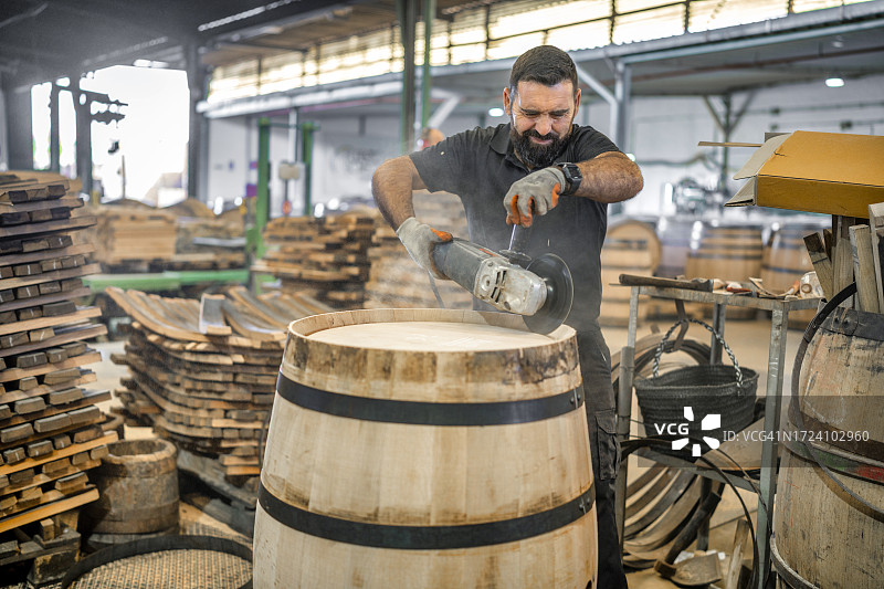 在赫雷斯的桶匠作坊中，制桶大师用砂纸和旋转打磨机对美国橡木进行精制和抛光图片素材