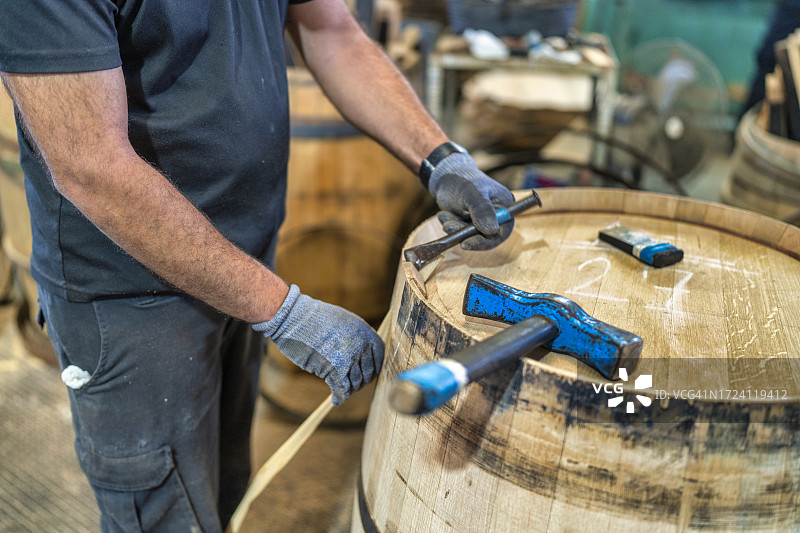 在赫雷斯的桶匠作坊里，工匠用锤子和凿子修理桶图片素材