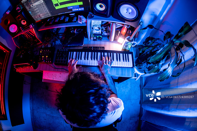 男人在音乐工作室弹奏键盘进行音乐创作或混音的俯视角度照片图片素材