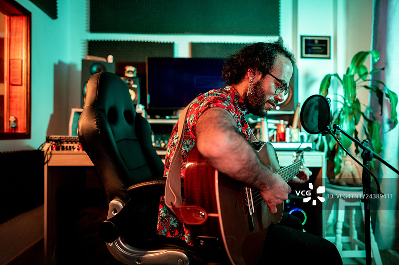 中年男子在音乐工作室弹吉他并录音图片素材