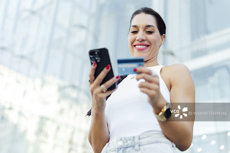 年轻漂亮的女人使用智能手机、信用卡和网上购物图片素材