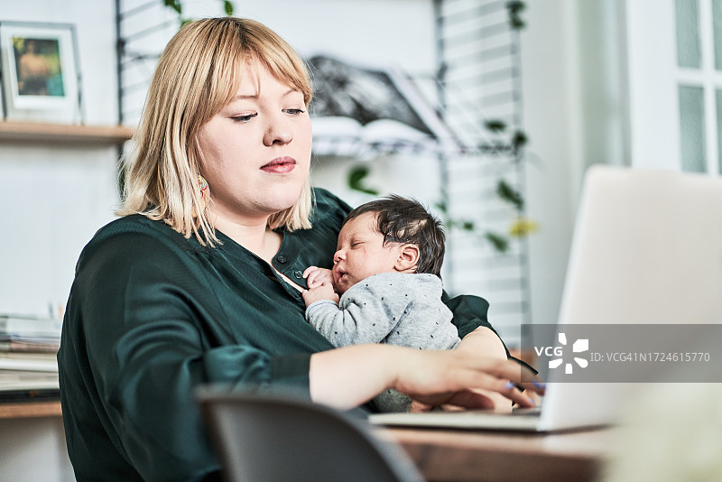 女人在家抱孩子用笔记本电脑图片素材