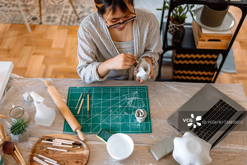 年轻女性用笔记本电脑在线学习陶艺图片素材