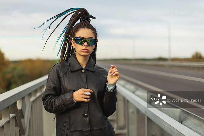 留着脏辫，身穿黑色外套的女人在桥上，街头风格图片素材