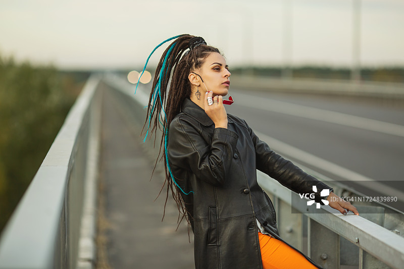 留着脏辫，身穿黑色外套的女人在桥上，街头风格图片素材