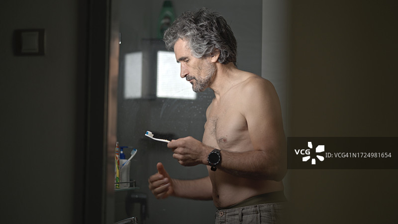 中年男人在浴室镜子前刷牙的生活瞬间图片素材