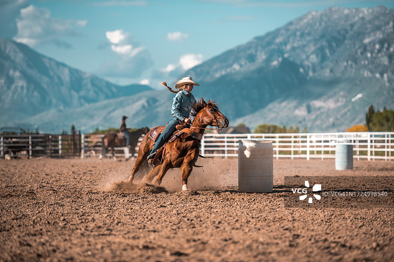 年轻女牛仔骑马绕桶赛图片素材