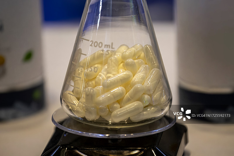 桌子上玻璃瓶中的彩色胶囊和药丸图片素材