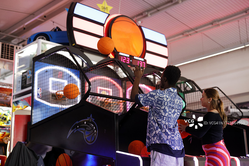 两名年轻人在英国海滨游乐场玩投篮机图片素材