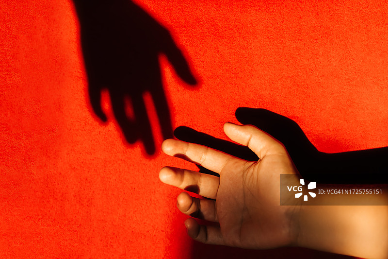 女人手伸向红色背景上的阴影图片素材