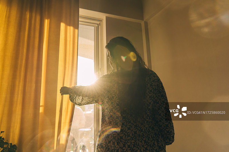 女人在阳光下关上窗帘图片素材