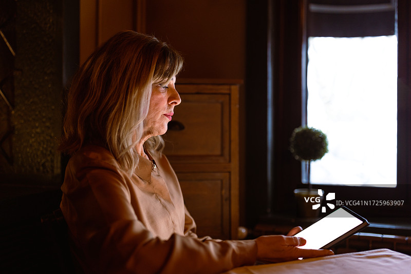 年长的女商人靠窗户使用平板电脑图片素材