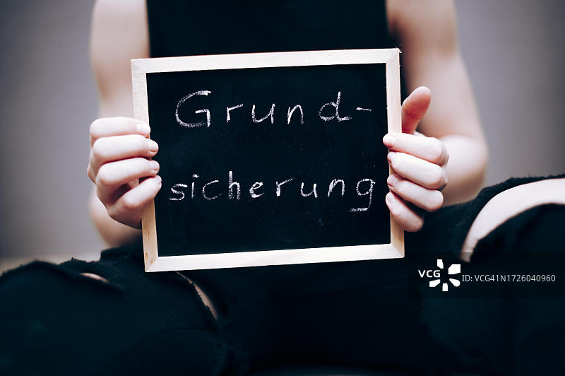 儿童基本保障的象征性图像，贫困儿童手持写有基本保障、国家支持的黑板图片素材