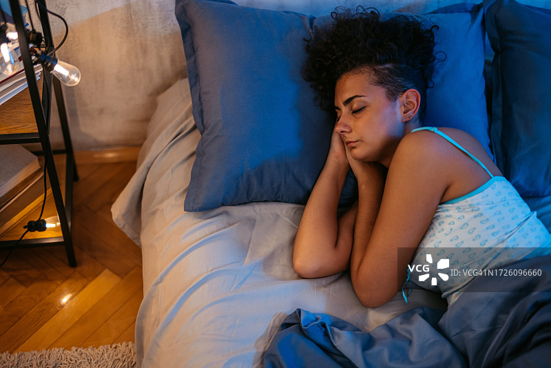 年轻女子夜晚在床上睡觉图片素材