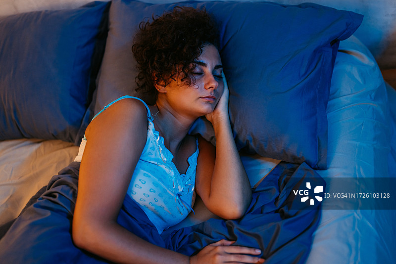 年轻女子夜晚在床上睡觉图片素材
