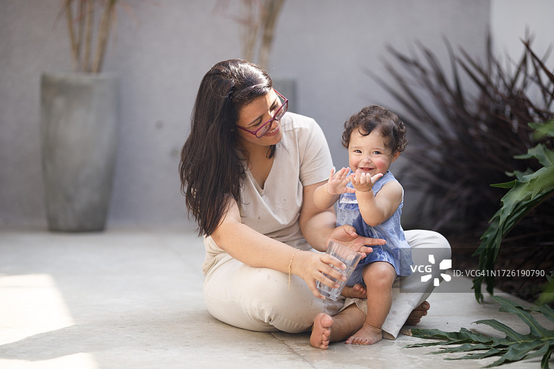女人和⼩女孩坐在地上，⼿里拿着⽔杯图片素材