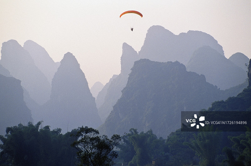 在喀斯特山脉上空玩滑翔伞图片素材