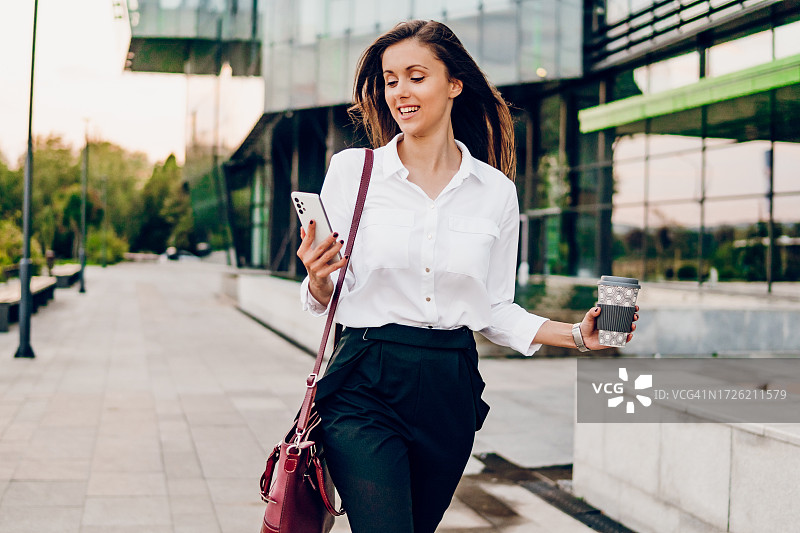 拿着智能手机赶去上班的商务女人图片素材