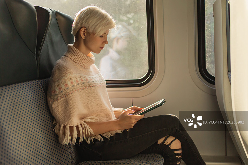 在火车上的使用平板电脑的金发女人图片素材