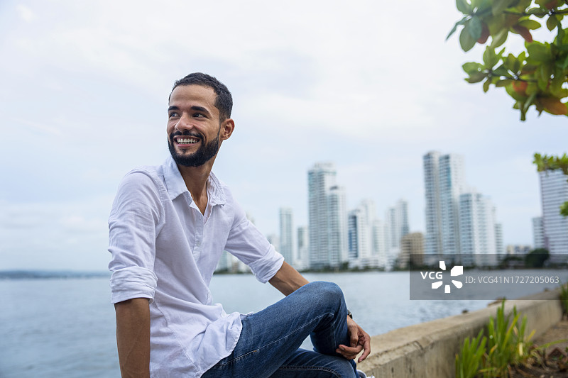 坐在哥伦比亚卡塔赫纳巴伊亚埃尔拉吉托围栏上的拉丁美洲男子图片素材