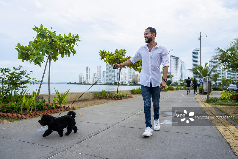 在哥伦比亚卡塔赫纳巴伊亚埃尔拉吉托与狗散步的西班牙裔男人图片素材