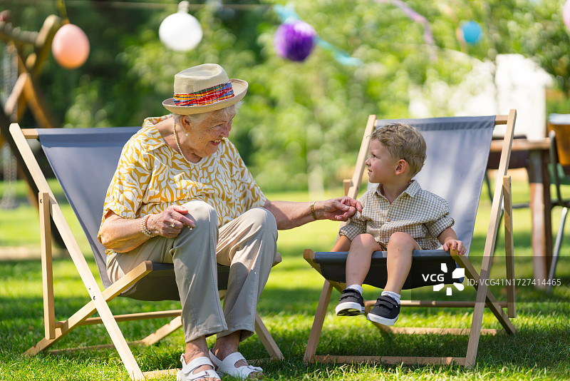 孙子和奶奶坐在躺椅上聊天图片素材